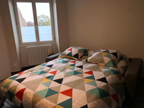 un lit avec une courtepointe colorée dessus dans une chambre dans l'établissement Le Petit Chaleureux - Centre ville - Wifi - stationnement (idéal couples, étudiants, business), à Niort