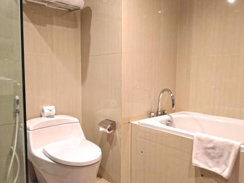 a bathroom with a white toilet and a bath tub at Swiss-Belhotel Makassar in Makassar