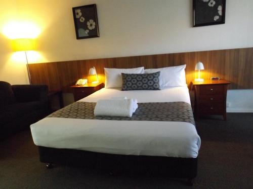 a hotel room with a large bed and two lamps at Central Court Motel Warrnambool in Warrnambool