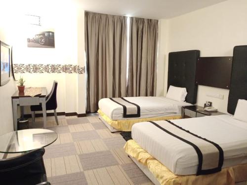 a hotel room with two beds and a desk at Shervinton Executive Boutique Hotel in Tawau