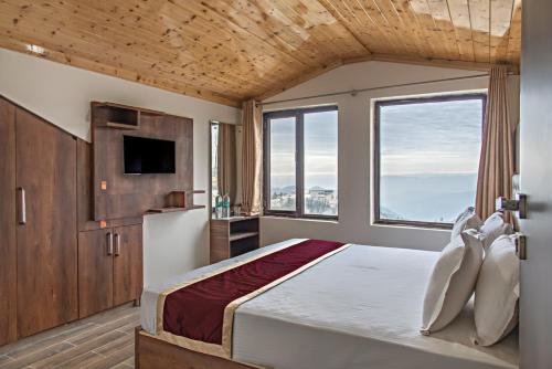a bedroom with a large bed with a large window at Snow Land Shimla in Shimla