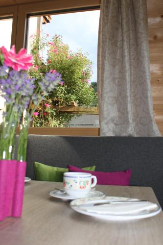 a table with a cup and a vase of flowers at Haus Alexander in Schladming