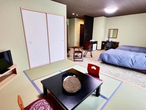 a room with a bedroom with a bed and a table at Apprising hotels GranJam Tsugaike in Otari