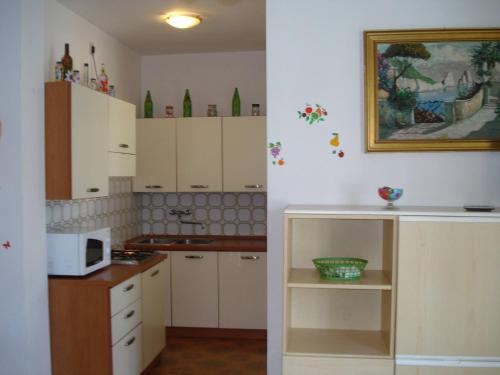a kitchen with white cabinets and a microwave at Newly renovated villa with private garden in Porto Santa Margherita di Caorle