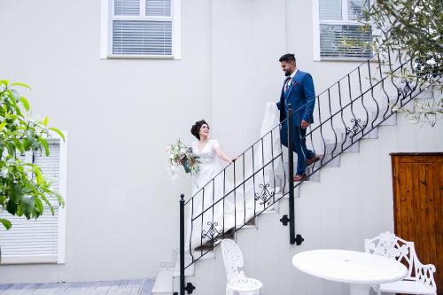 a bride and groom walking down the stairs at their wedding at Burkleigh House in Johannesburg