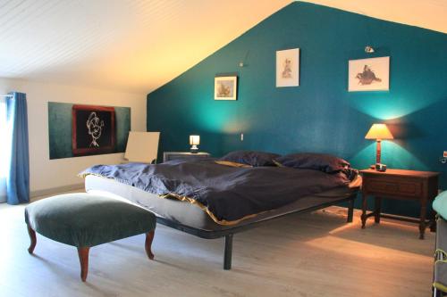 1 dormitorio con 1 cama grande y pared azul en Maison de charme, d'artiste, décoration brocante, en Aigrefeuille-dʼAunis