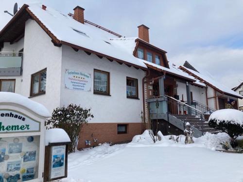 a snow covered house with a sign in front of it at Pension Höchemer in Bad Bocklet