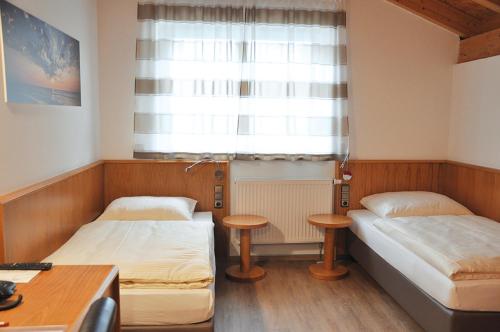 a small room with two beds and a window at Garni Hotel Alber in Marktl