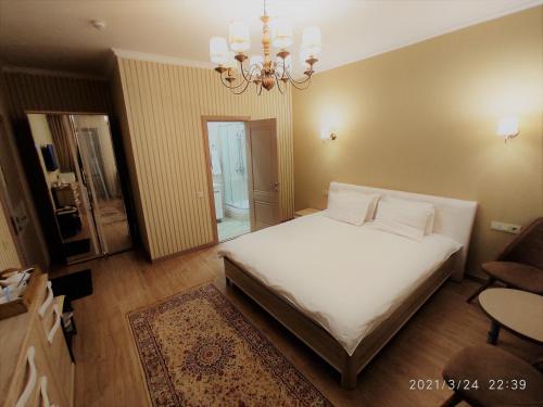 a bedroom with a large white bed and a chandelier at Altyn in Astana