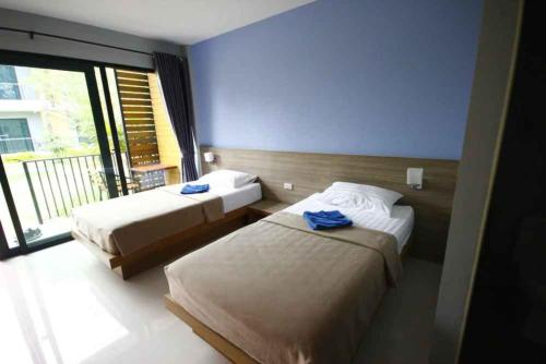 a hotel room with two beds and a large window at Phumi Resort in Thalang