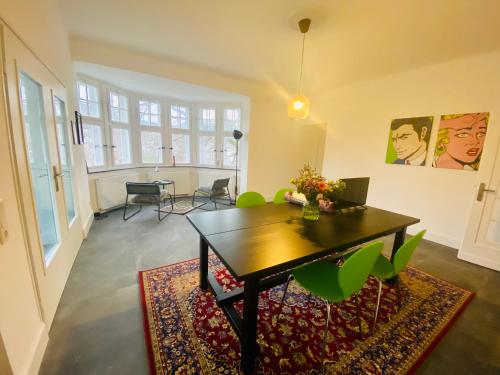 a living room with a table and green chairs at Get-your-flat Traumhafte Altbau-Wohnung in Denkmal-Villa 3 Zr Kü Bad 2 Schlafzr 125 m2 Haustier auf Anfrage - ruhig & naturnah in Hagen