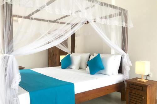 um quarto com uma cama de dossel com almofadas azuis e brancas em The Blue Haze Weligama em Weligama