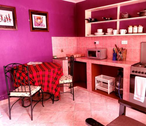 a kitchen with pink walls and a table and chairs at Kundayo Serviced Apartments Lodge in Arusha