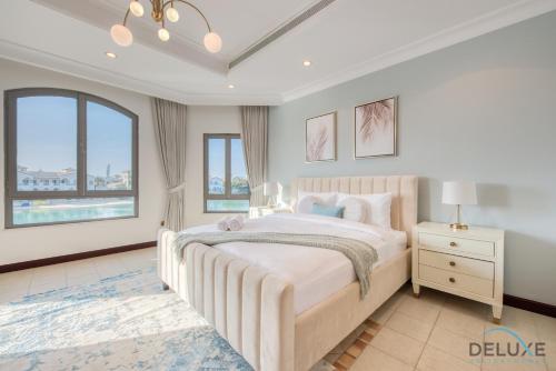 a white bedroom with a large bed and windows at Breath-taking 6BR Villa in Frond E Palm Jumeirah by Deluxe Holiday Homes in Dubai