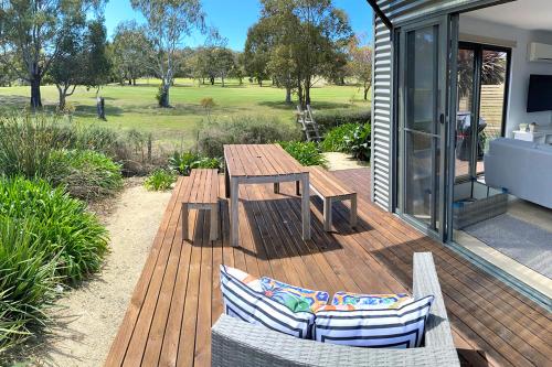 une terrasse en bois avec une table et des chaises en bois dans l'établissement Fairways 1, à Coles Bay