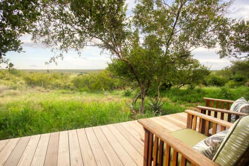 a wooden deck with chairs and a view of a field at Klaserie Drift Misava in Klaserie Private Nature Reserve