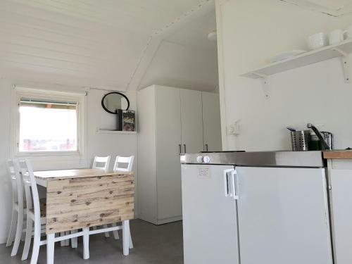 a kitchen with a table and a white refrigerator at First Camp Duse Udde - Säffle in Säffle