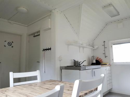 a kitchen with a wooden table and white chairs at First Camp Duse Udde - Säffle in Säffle