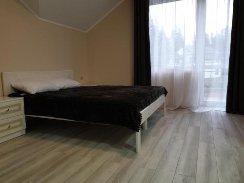 a bedroom with a bed and a large window at Hotel Osher in Bukovel
