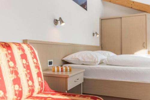 a bedroom with a bed and a chair and a table at Runcac Apt Gomina in San Vigilio Di Marebbe