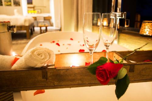 a bath tub with two champagne glasses and roses at Klaserie Drift Misava in Klaserie Private Nature Reserve