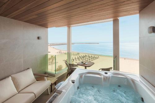 a bath tub in a room with a view of the beach at BIO BEACH Boutique Hotel - Adults Only in Rethymno Town