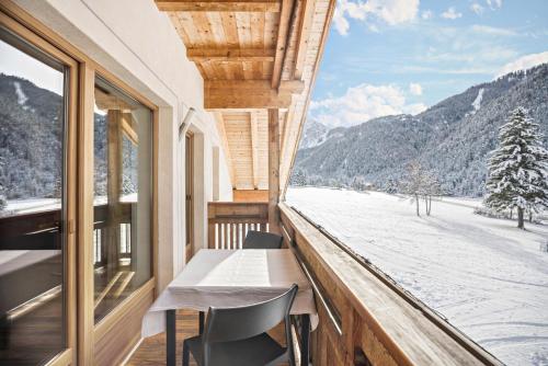 a balcony with a table and chairs and a view of the snow at Runcac Apt Pla in San Vigilio Di Marebbe