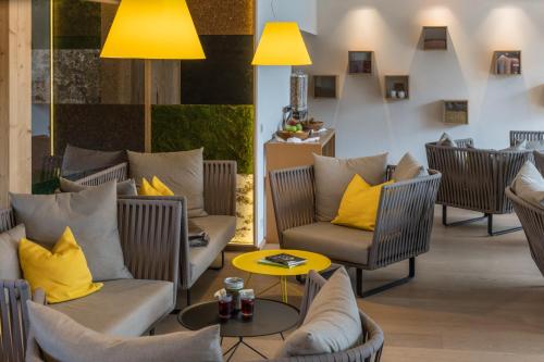 a lobby with chairs and tables and yellow pillows at G'sund & Natur Hotel Die Wasnerin - Adults Only in Bad Aussee