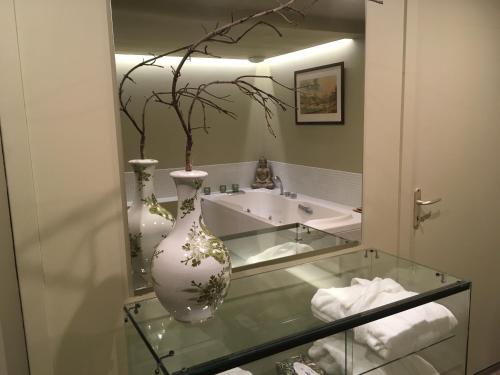 a bathroom with a sink and a vase on a glass table at L'ATELIER ET APRES in Anet