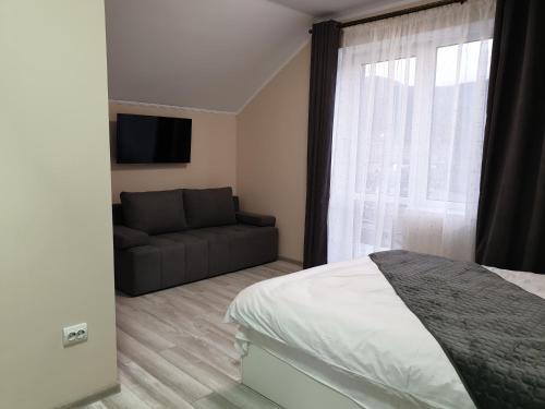 a bedroom with a bed and a couch and a window at Hotel Osher in Bukovel