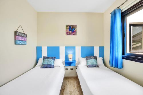 twee bedden in een kamer met blauwe en witte strepen bij Casa Puerto del Tostón in Cotillo