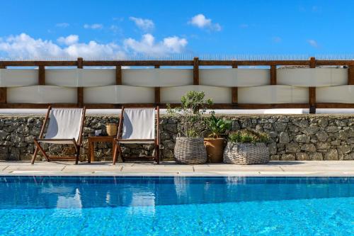 a couple of chairs and a swimming pool at Pelican Bay Hotel in Platis Yialos Mykonos