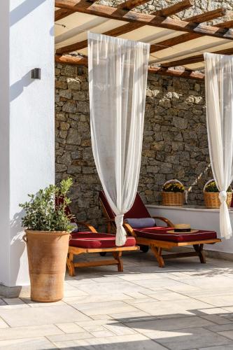 a patio with two chairs and a curtain at Pelican Bay Hotel in Platis Yialos Mykonos