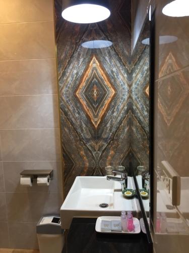 baño con lavabo y pared de azulejos en Ben Guesthouse, en Chiang Rai