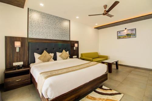 a bedroom with a large bed and a green chair at Mountain Breeze Resort, Mahabaleshwar in Mahabaleshwar