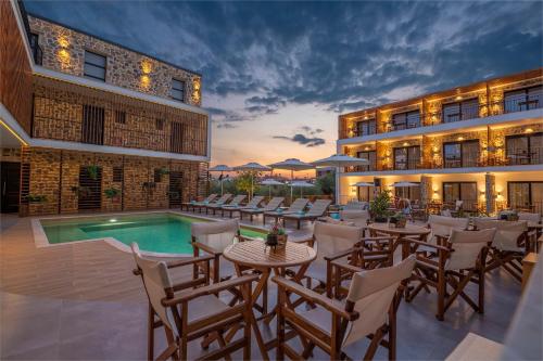 eine Hotelterrasse mit Tischen und Stühlen neben einem Pool in der Unterkunft Dandelion Suites in Nikiti