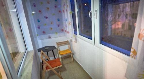 a room with two chairs and a table and two windows at Apartament 2 camere cu loc de parcare in Cluj-Napoca