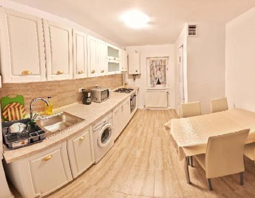 a kitchen with white cabinets and a sink and a table at Apartament 2 camere cu loc de parcare in Cluj-Napoca