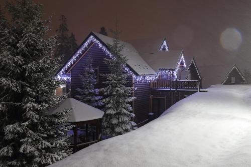 a house with christmas lights on it in the snow at Bukovel Hotel in Bukovel