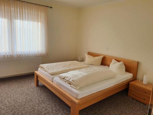 a bedroom with a bed with white sheets and a window at Landhaus Braband Ferienwohnungen - Cuxhavener Straße 96 in Cuxhaven