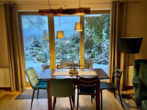 a dining room table and chairs in front of a large window at Apartament Grafitowy Willa Laser in Szklarska Poręba