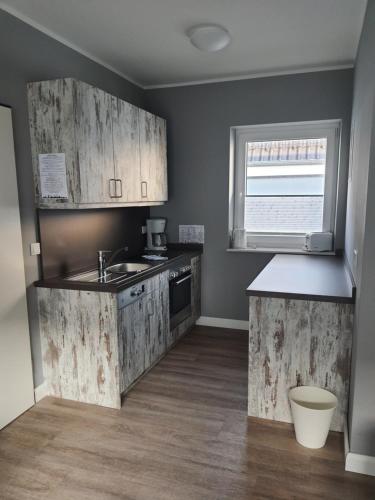 a kitchen with wooden cabinets and a sink and a window at Landhaus Braband Studios - Rugenbargsweg 17 in Cuxhaven