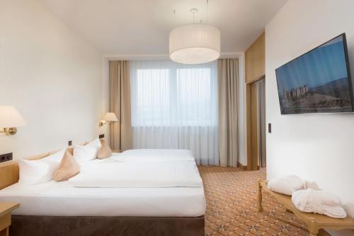 a hotel room with two beds and a large window at Best Western Ahorn Hotel Oberwiesenthal – Adults Only in Kurort Oberwiesenthal