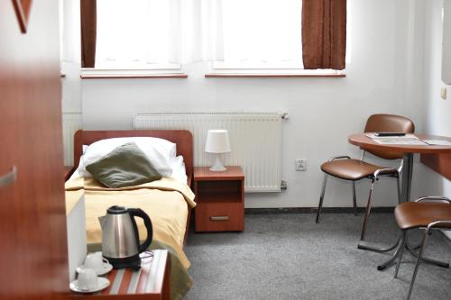 Hotel Dąbrowiak في دونبروفا جورنيتشا: غرفة نوم بسرير وطاولة وكراسي