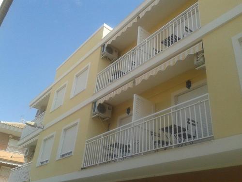a yellow building with white balconies with a dog sitting on it at Apartamentos Margoysa I in Los Alcázares