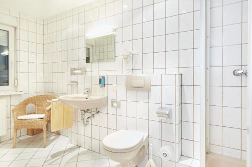 a white bathroom with a toilet and a sink at Park Hotel Berlin in Bad Fallingbostel