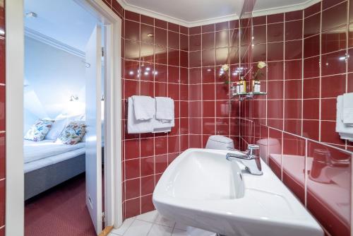 uma casa de banho em azulejos vermelhos com um lavatório e uma cama em Kronen Gaard Hotel em Sandnes