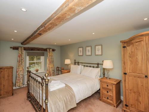 ein Schlafzimmer mit einem großen Bett und einem Holzschrank in der Unterkunft Rose Cottage in Penrith