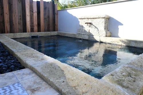 una piscina d'acqua accanto a una recinzione di legno di La maison de Flore a Pernes-les-Fontaines