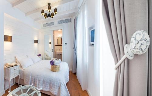 a white bedroom with a bed and a chandelier at Ela Tenedos Hotel - Special Category in Bozcaada
